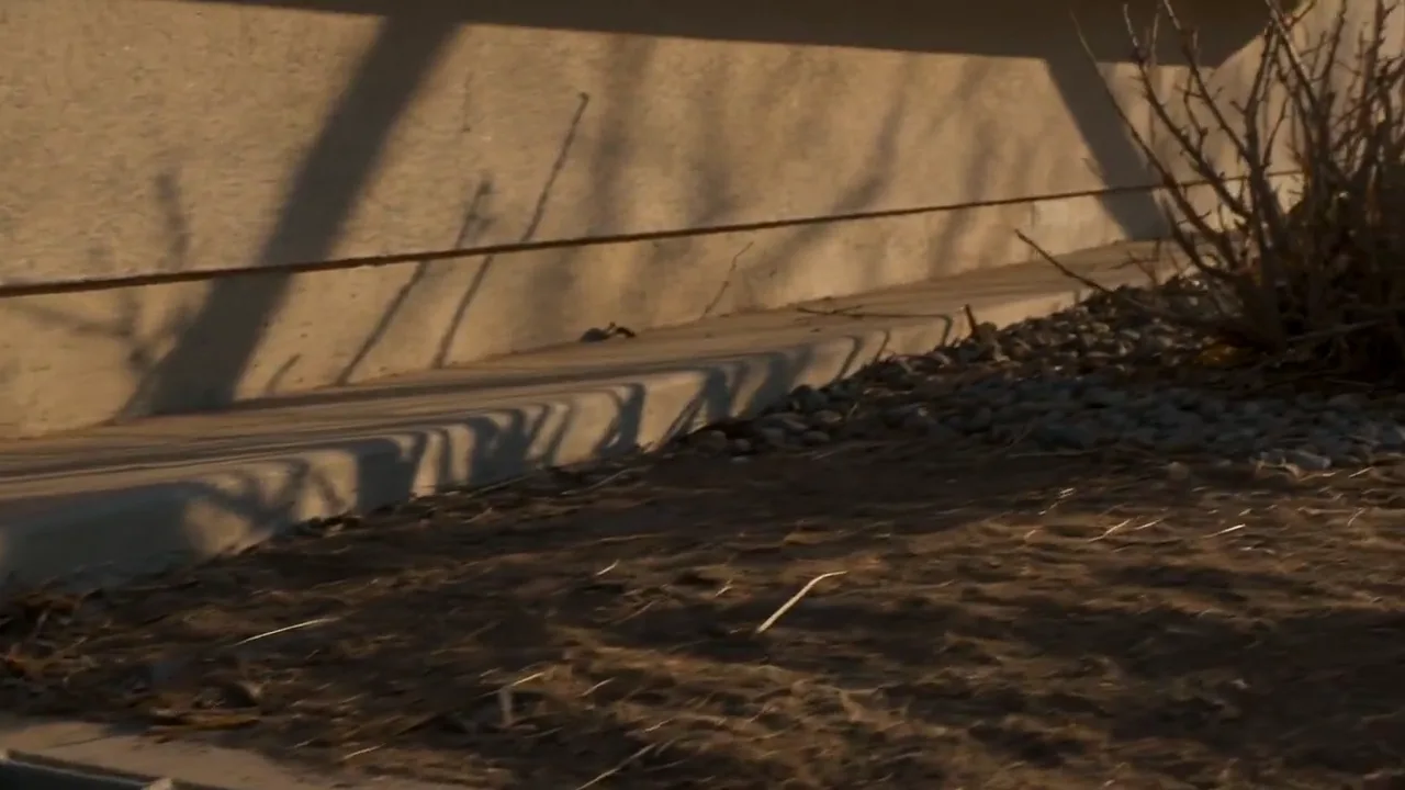 The base of a stucco wall meeting a gravel bed in low evening light